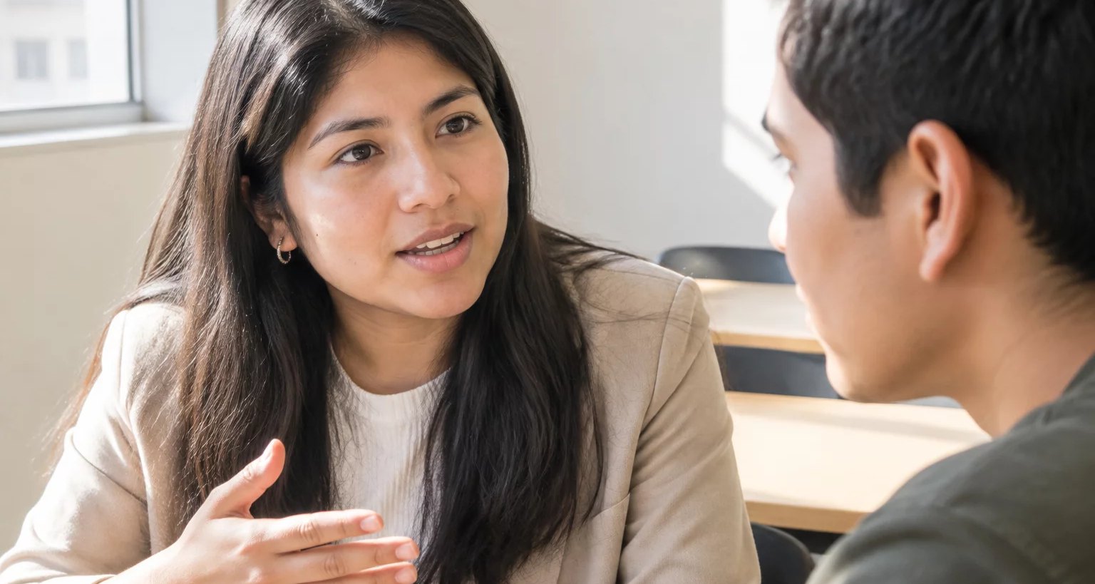 Dos personas conversando de cerca en una sala clara